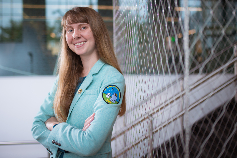 Skylar Larsen smiles indoors, and her jacket has a patch that says “MIT Wallace Astrophysical Observatory.