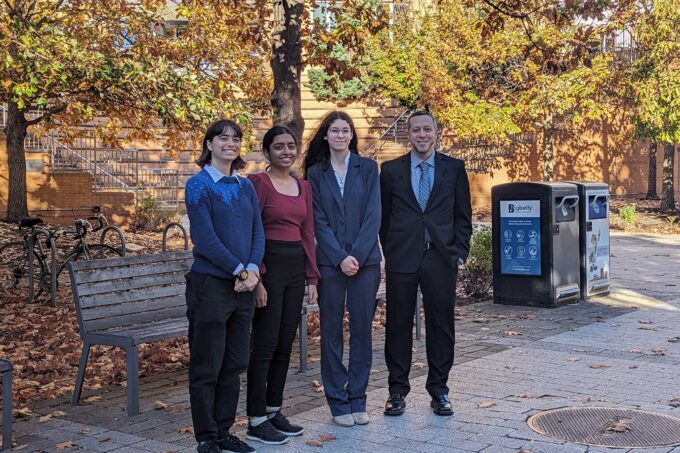 Ella Sheffield, Prajna Nair, Erin Cusson, and Tim Brothers stand together smiling. They are outside MIT's Stata Center in fall.
