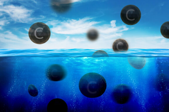 Black spheres with the letter “C” on them, representing carbon molecules, float out of the water.