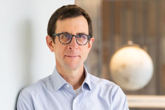 Headshot of David McGee with an out-of-focus globe in the background.