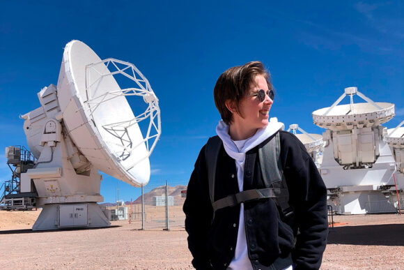 Jess Speedie sounds outside with one of the Atacama Large Millimeter/submillimeter Array (ALMA) dishes behind her.