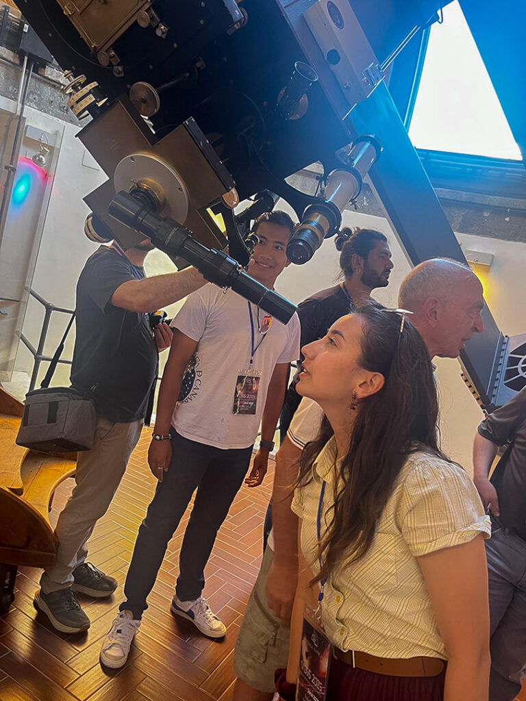 Isabella Marcias looks through the eye piece of a large telescope.