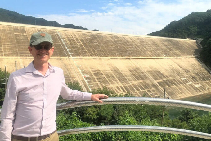 Tom Herring stands in front of a large dam.